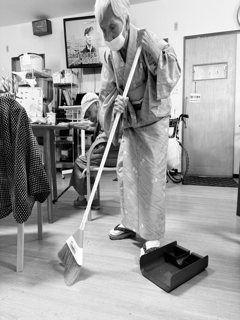 利用者がほうきで床を掃除している様子