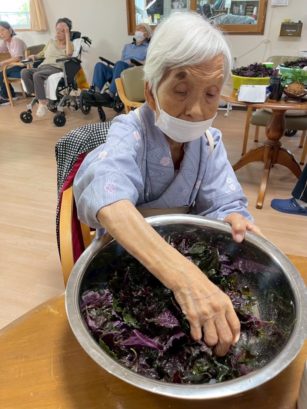 利用者が大きなボウルで野菜を混ぜている様子