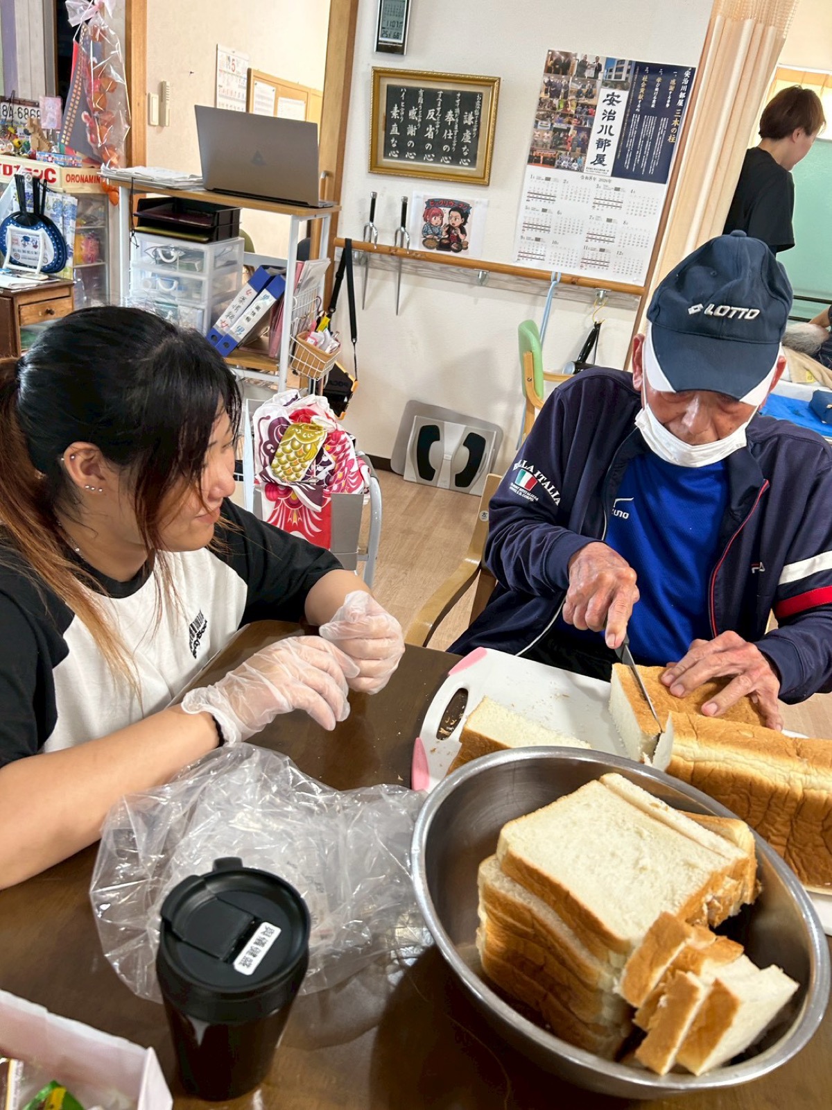利用者とスタッフがテーブルでサンドイッチを作っている様子