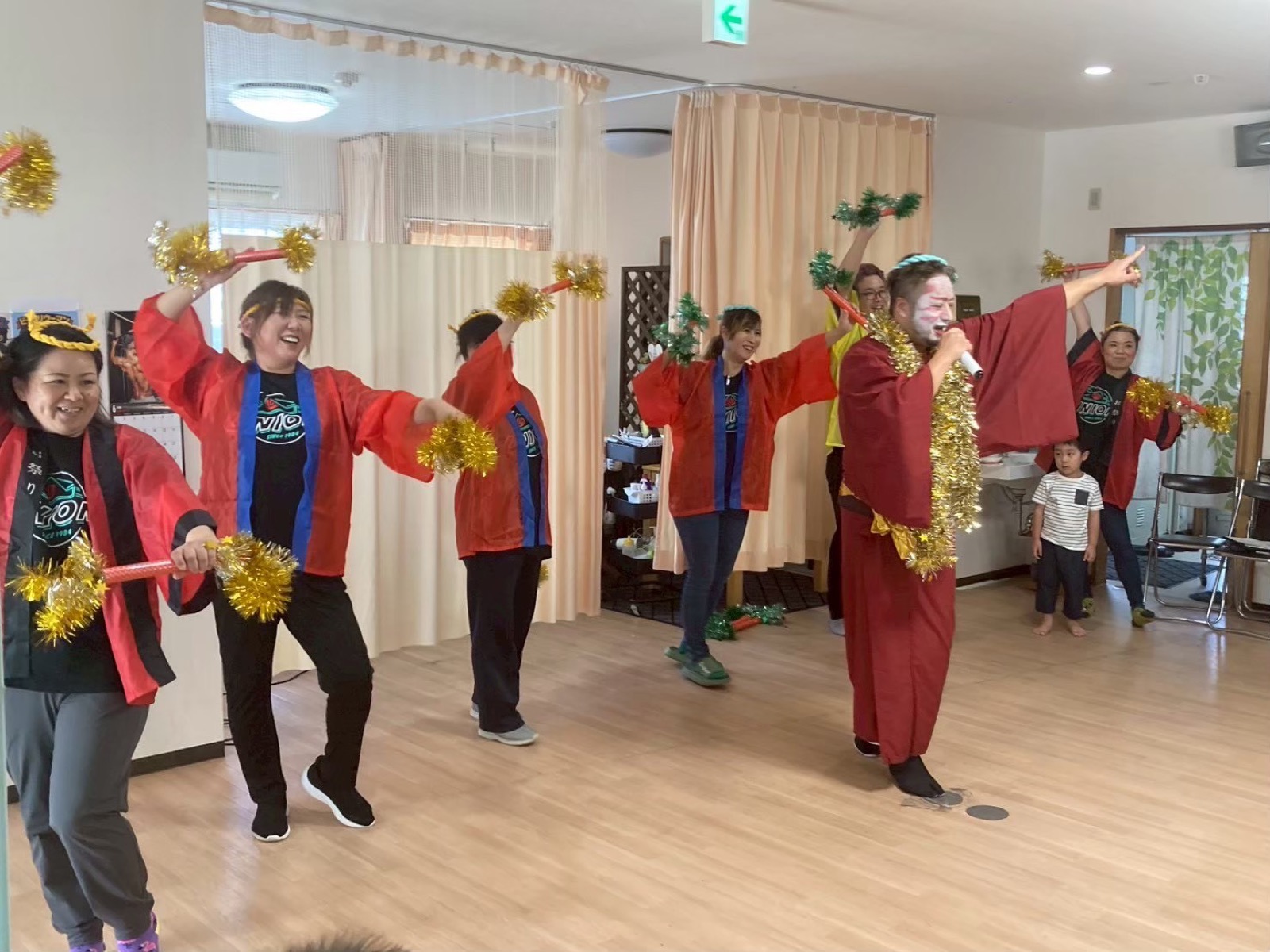 ホールでポンポンを持って踊るスタッフと利用者